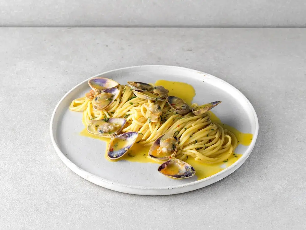 Pyszne Spaghetti con le Vongole przepis: makaron z małżami w sosie na talerzu.