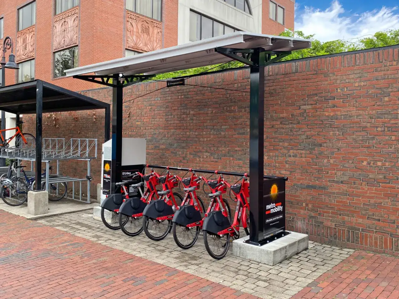 Stacja ładowania rowerów elektrycznych z czerwonymi rowerami gotowymi do jazdy. Panele słoneczne nadają jej ekologiczny charakter.