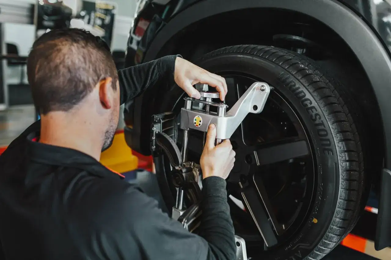 Técnico ajustando un coche con equipo de alineación. Averigua cuanto cuesta alinear un coche para un manejo óptimo.