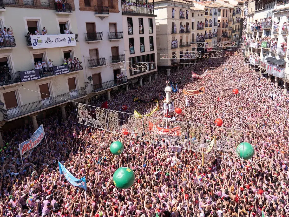 Multitud celebra cuando son vaquillas en Teruel. Balcones llenos de gente observan la fiesta.