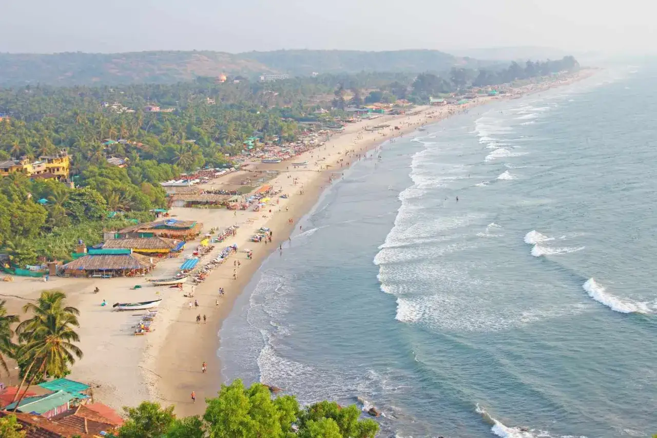 Goa kiedy jechać? Piękna plaża z palmami, chatkami i turystami. Idealne miejsce na wakacje.