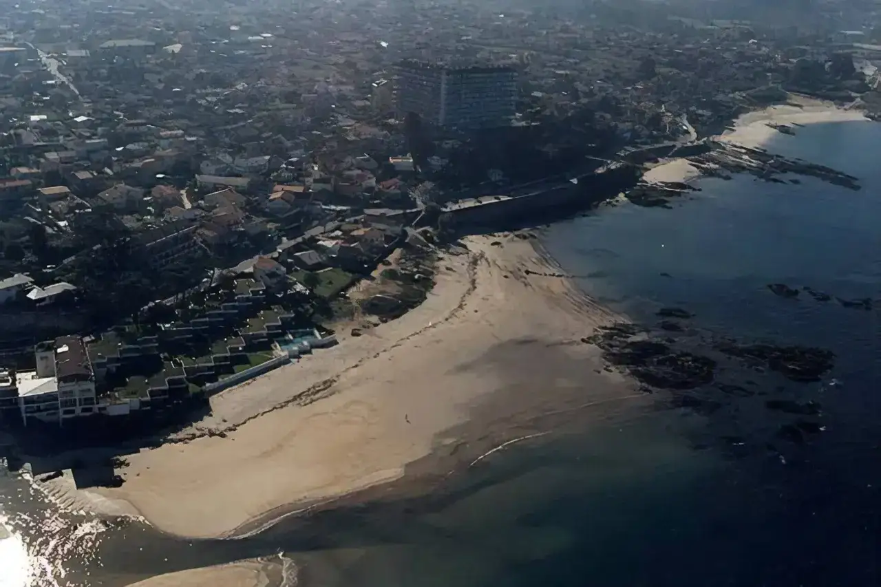 Vista aérea de la costa de a calzoa vigo, con playas, rocas y edificios residenciales.