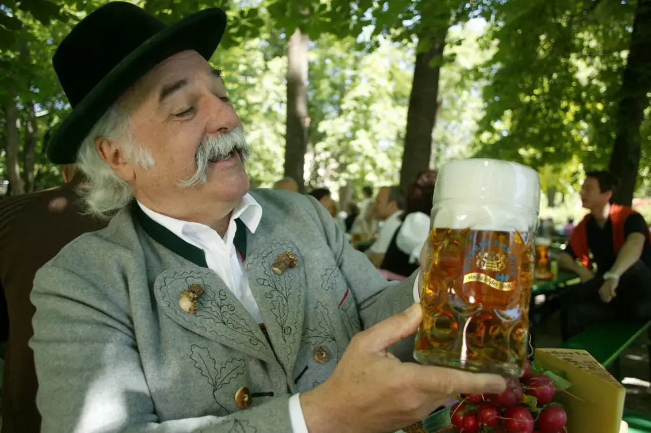 Bayerischer Mann mit Hut und Tracht h&auml;lt ein Bierglas. Bier ist ein Grundnahrungsmittel in Bayern.