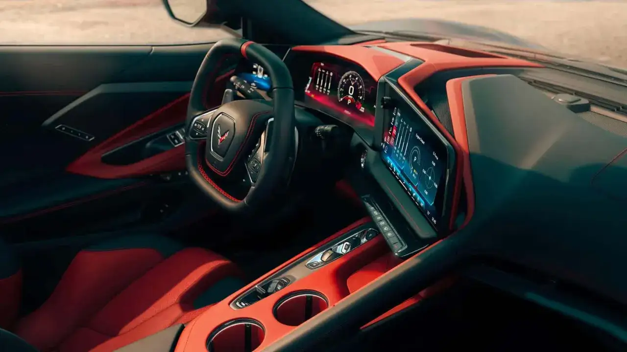 Wnętrze Corvette Stingray z czerwono-czarną tapicerką, cyfrowymi zegarami i ekranem multimedialnym.