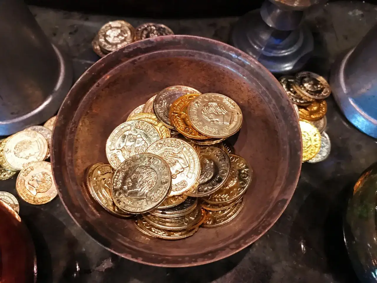 Ein Haufen goldener und silberner Münzen in einer Schale. Sie symbolisieren den Wert von 7 Jahren Ehe, eine Zeit voller Schätze und gemeinsamer Erlebnisse.