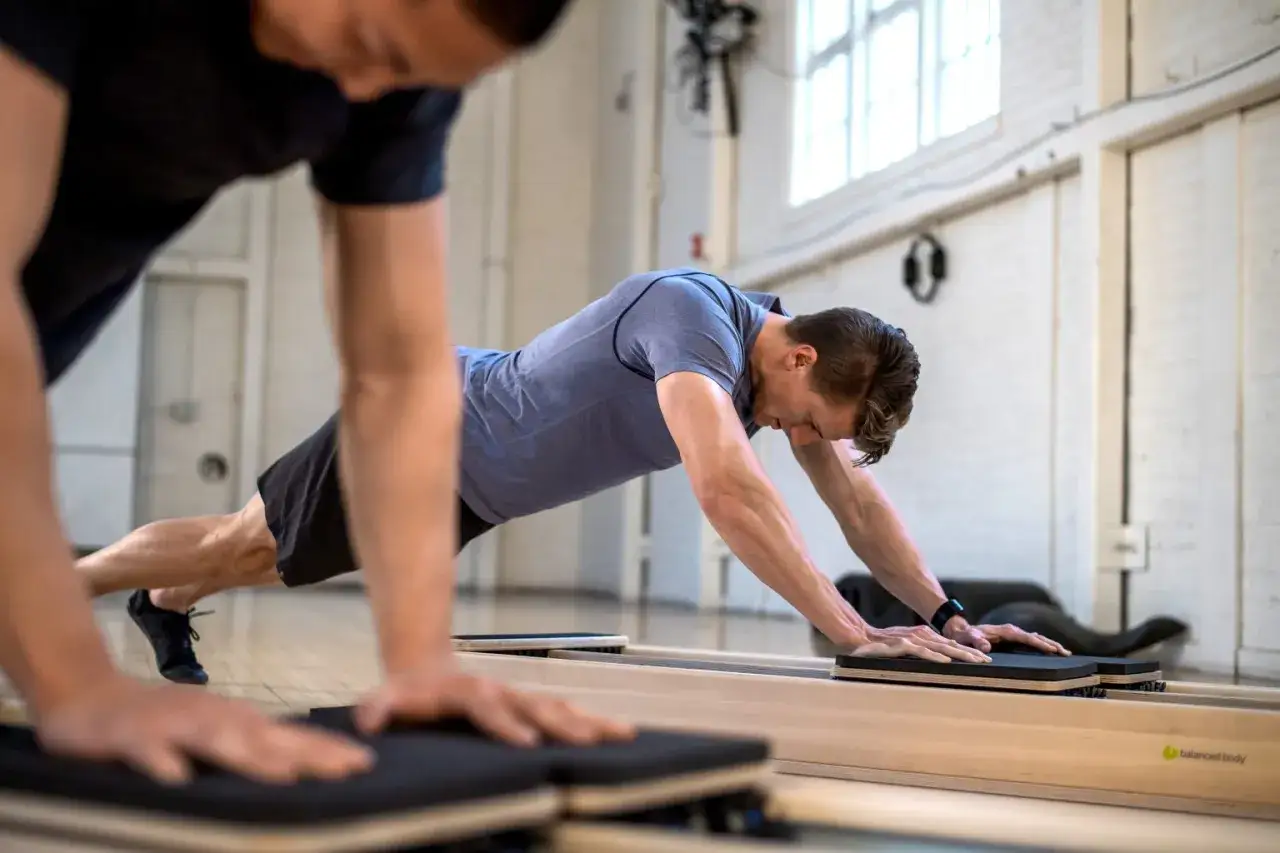 Två män tränar pilates på reformer-maskiner. Johanna Hector inspirerar till rörelse.