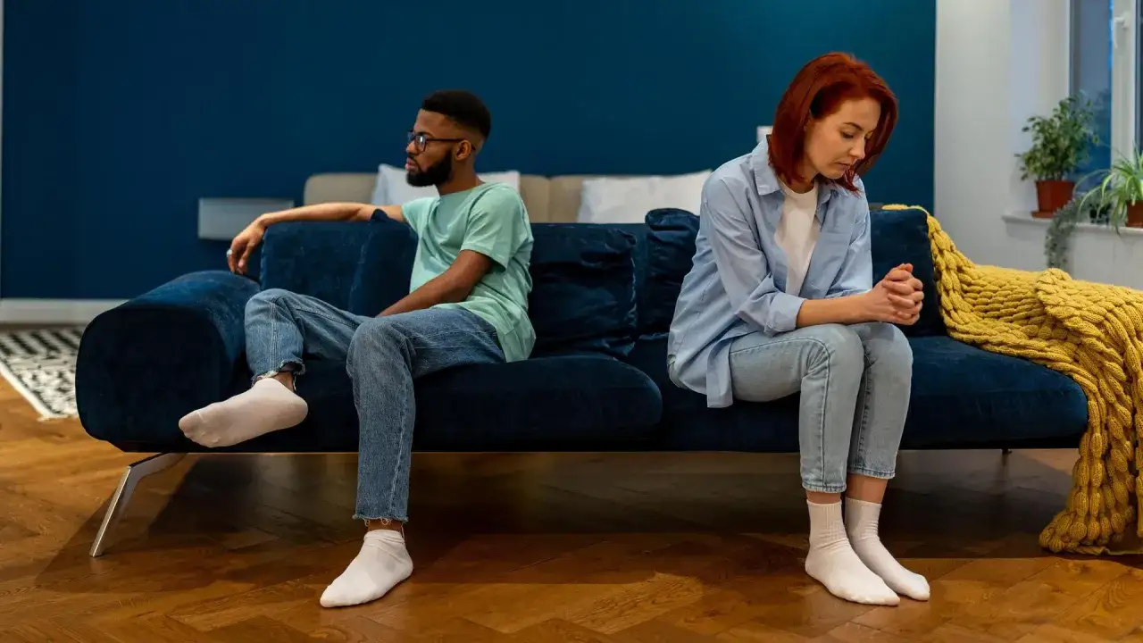 Ein Paar sitzt auf einem Sofa, getrennt und nachdenklich. Ein Mann und eine Frau, die überlegen, wie sie ihre **Beziehung retten, wenn der Partner nicht mehr will**.
