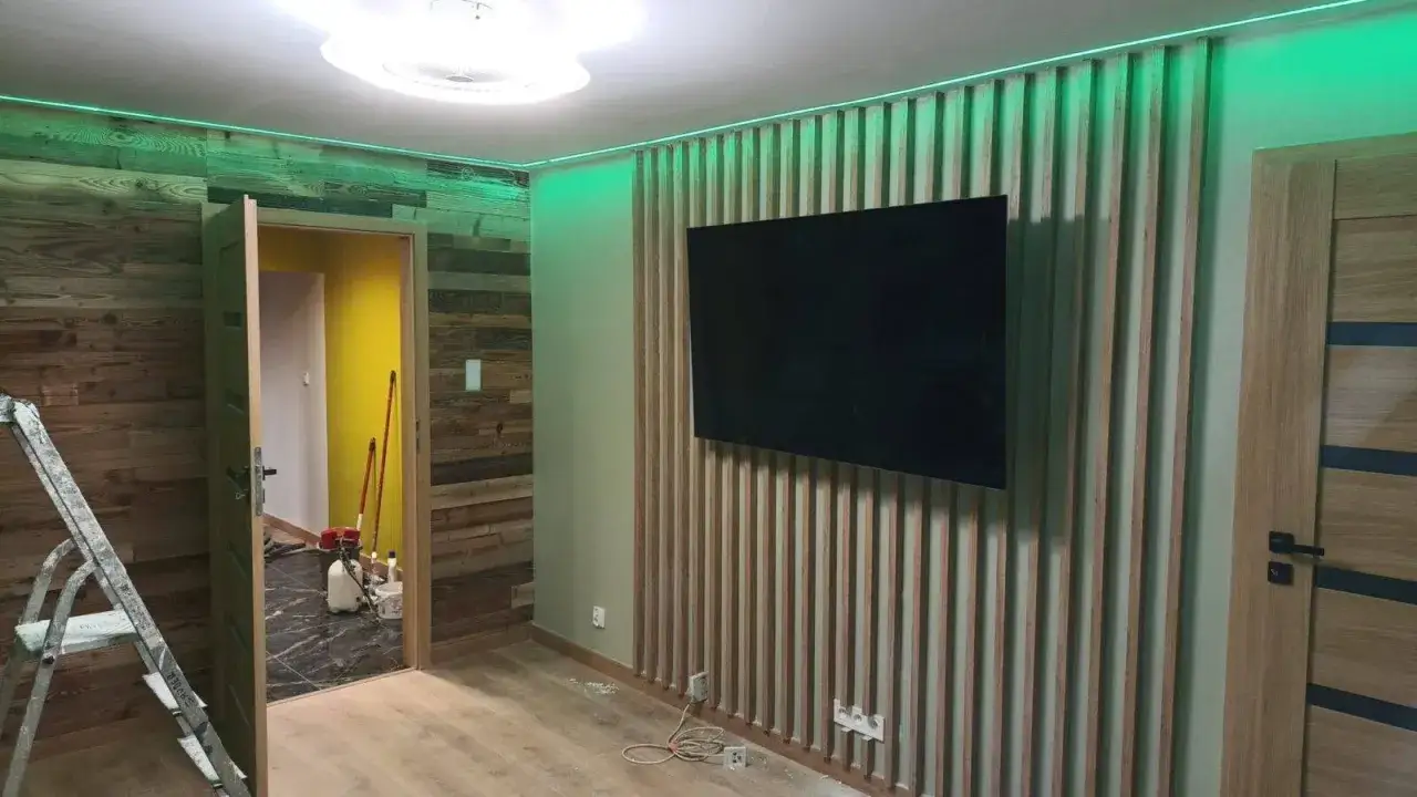 Nowoczesne wnętrze z drewnianą boazerią, telewizorem i zielonym oświetleniem.