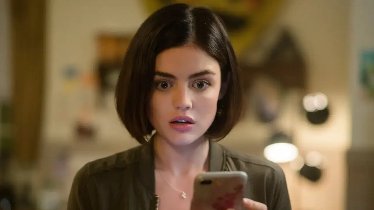 Lucy Hale sorpresa mentre guarda il telefono, un'attrice nota per i suoi film e programmi TV.