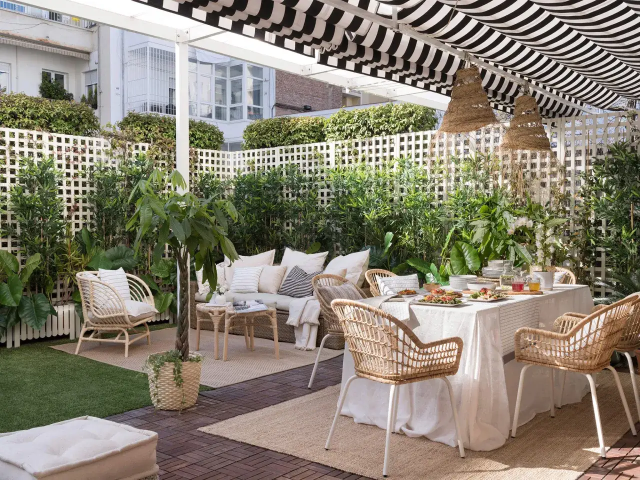 Un rinc&oacute;n de intimidad en la terraza de un &aacute;tico, con mobiliario de rat&aacute;n y una mesa puesta para disfrutar.