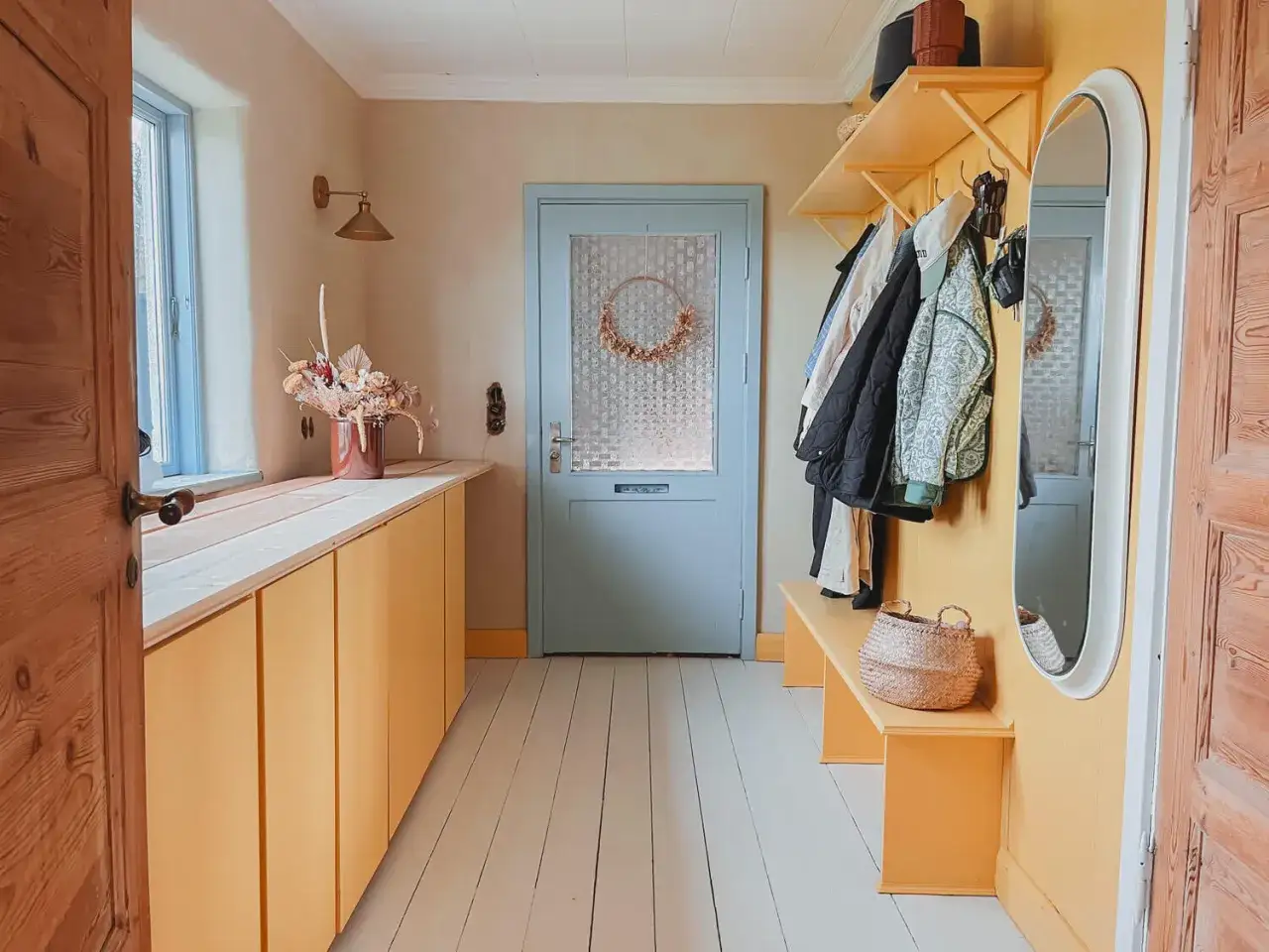 Warme flur farbe ideen: gelbe Schr&auml;nke, Garderobe und Bank, hellblaue T&uuml;r, Holzboden.