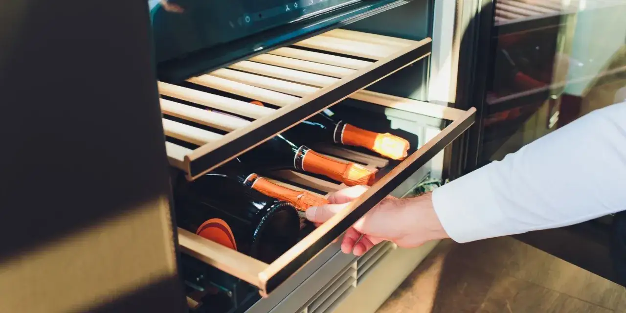 Mann entnimmt Flaschen aus einem Weink&uuml;hlschrank. So wissen Sie, wie lange ist offener Wein haltbar.