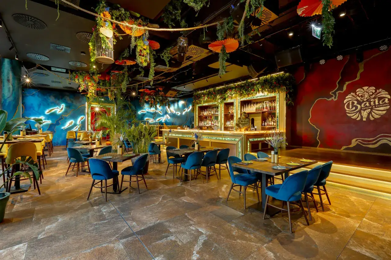 Egzotyczne wnętrze restauracji z neonowym motywem ryb i bujną roślinnością. Idealne miejsce na kolację w jednej z top restauracji Warszawa.