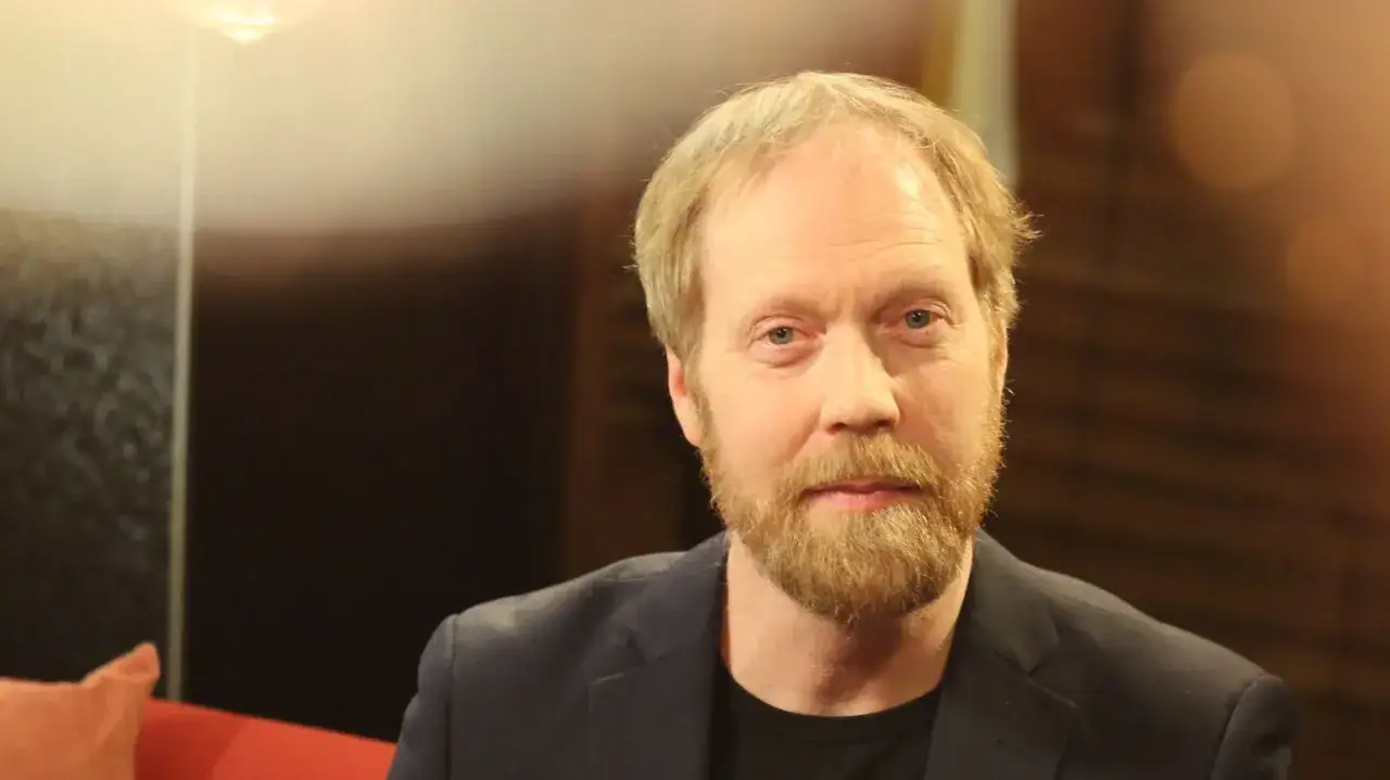 Lars Johan &Aring;ge, en man med blont h&aring;r och sk&auml;gg, b&auml;r en m&ouml;rk kavaj.