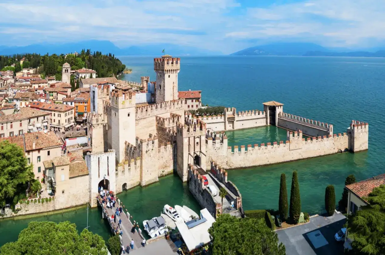 Le château Scaligère de Sirmione, sur le lac de Garde, se dresse fièrement sur l'eau turquoise. Une passerelle mène à son entrée fortifiée.