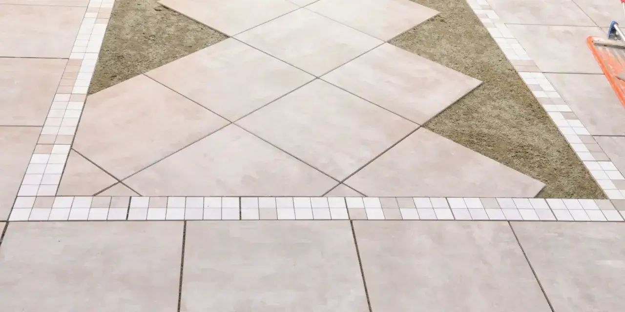 Calepinage terrasse carrelage : pose de carreaux de grès cérame beige en diagonale, bordée de mosaïques blanches et beiges, sur un lit de sable.