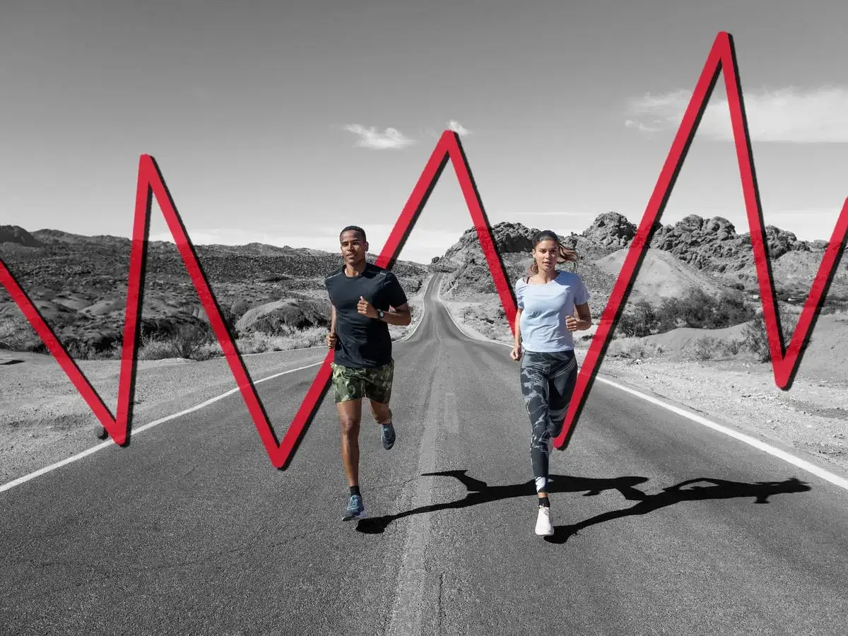 Co to jest tempo run? Ujęcie pary biegaczy na pustej drodze, z czerwoną linią wykresu pulsu nad nimi.