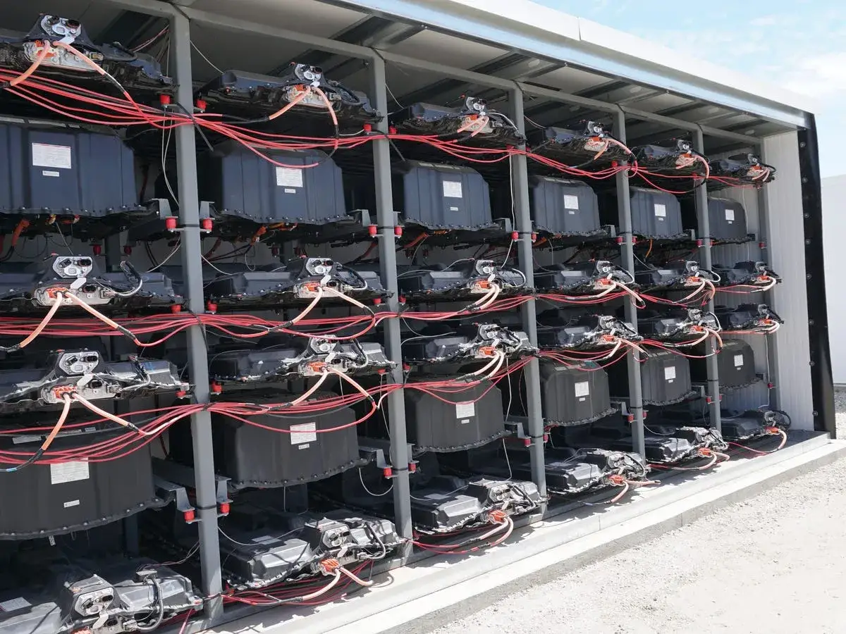 Reihen von schwarzen Batteriemodulen, verbunden mit roten Kabeln, bilden eine beeindruckende **Autobatterie als Solarspeicher**-Anlage.