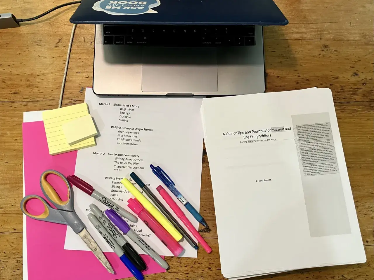 Ordenados recursos para escritores: portátil, tijeras, marcadores y hojas con guías para escribir memorias y relatos de vida.