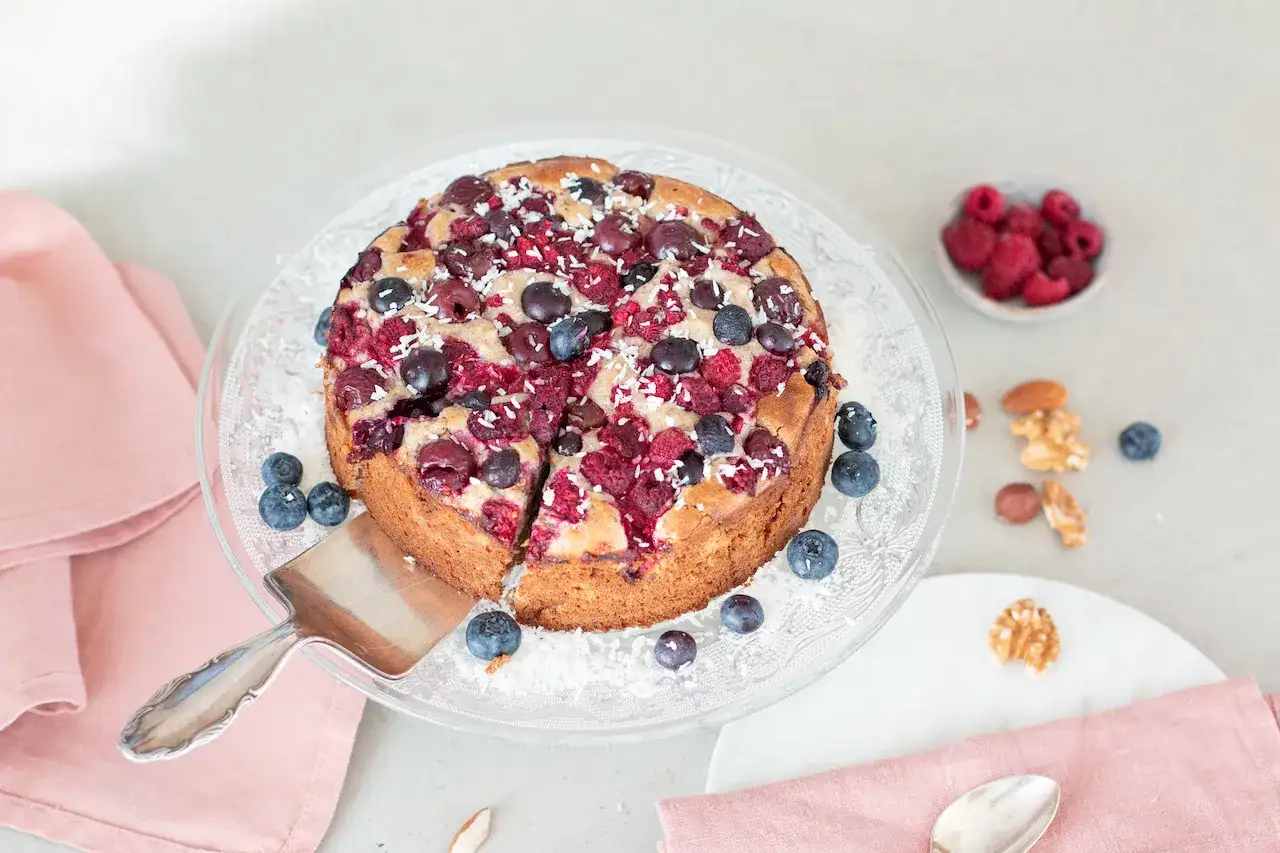 Saftiger Beerenkuchen, perfekt für Diabetiker. Mit Kirschen, Himbeeren und Blaubeeren belegt, bestreut mit Kokosraspeln.