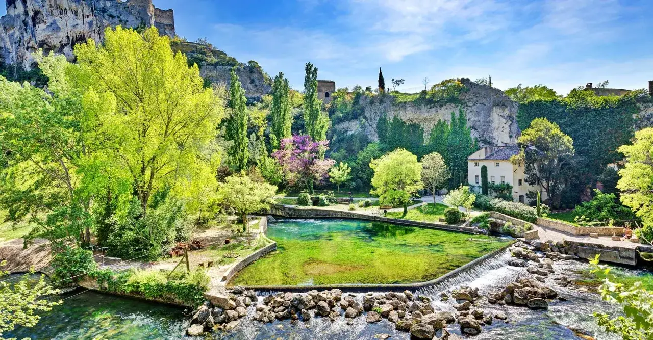 Magnifique source d'eau turquoise, entourée de verdure et de falaises, avec un château en ruines. Une activité gratuite Vaucluse idéale pour se ressourcer.