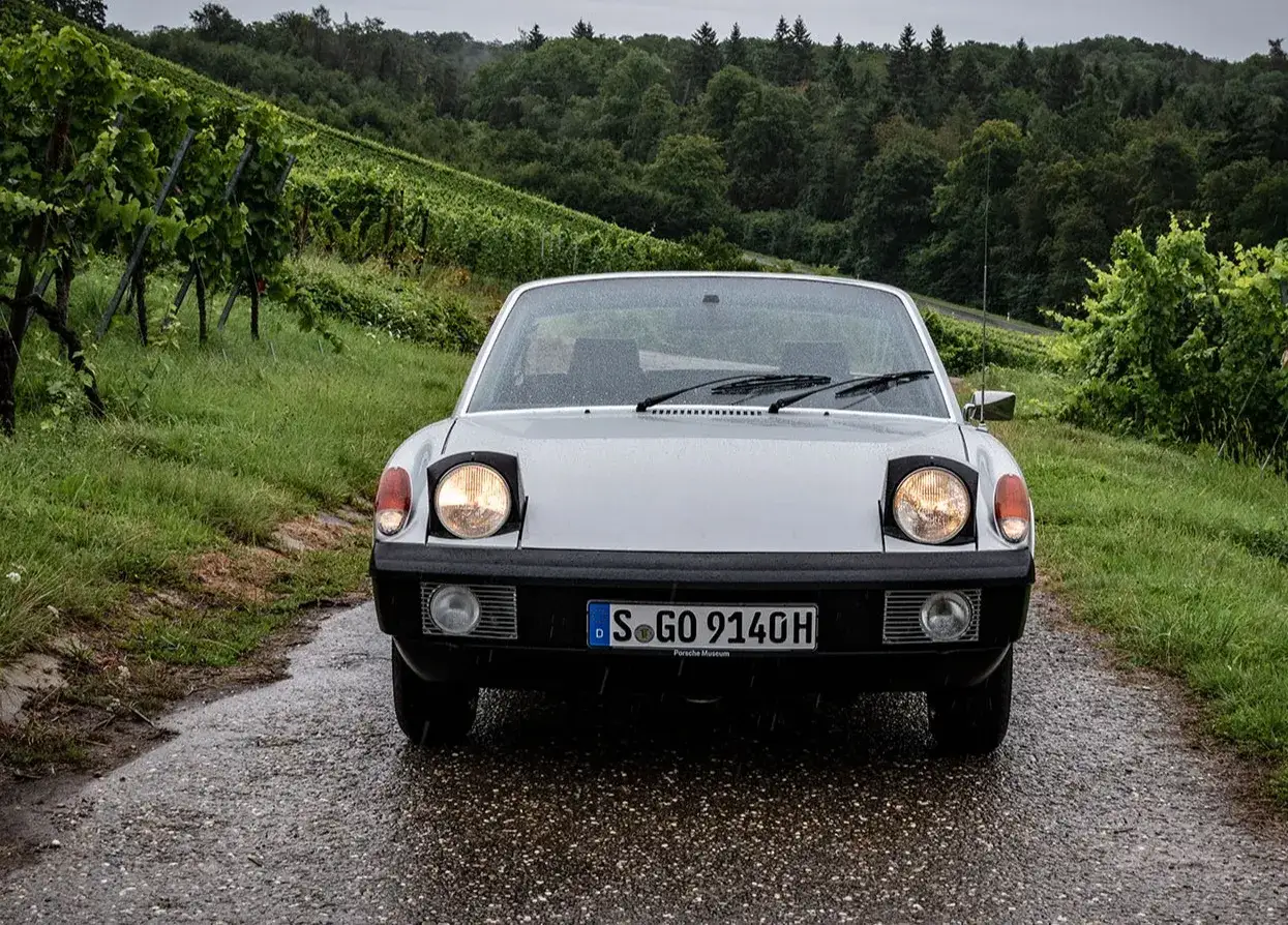 Silberner Porsche 914 auf nasser Straße, umgeben von Weinbergen. Die **Porsche 914 Preisentwicklung** zeigt steigende Werte für diesen Klassiker.