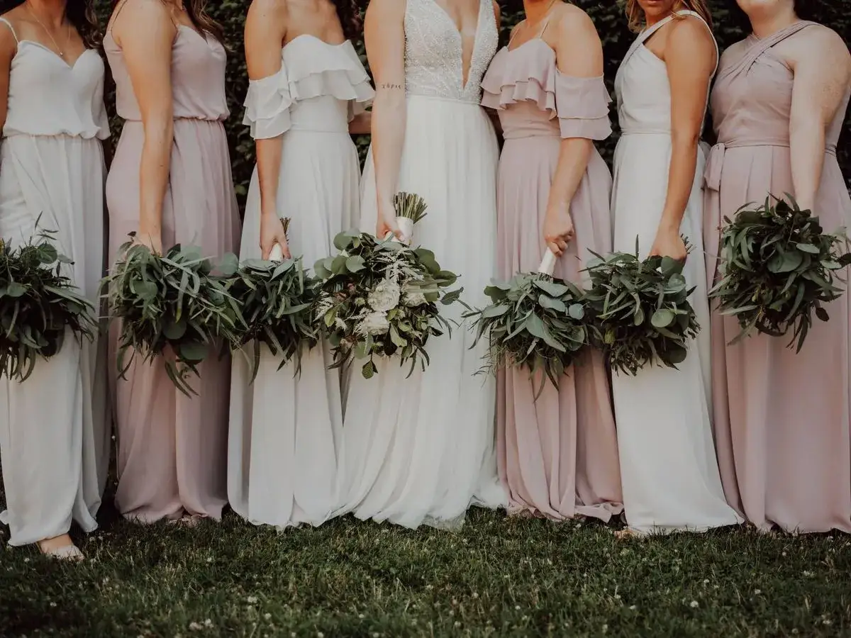 Las damas de honor, todas solteras, lucen vestidos vaporosos y ramos verdes.