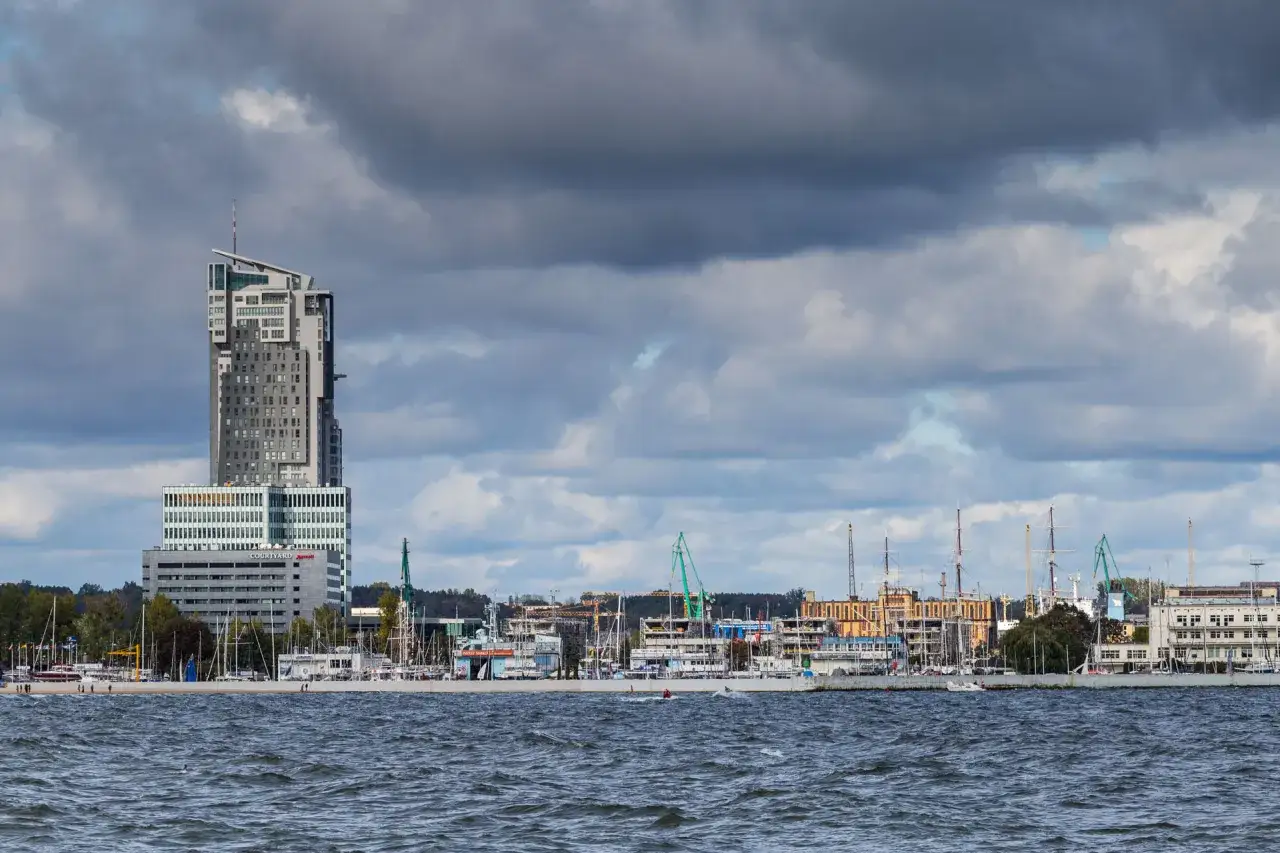 Hotel Marriott Gdynia góruje nad portem pełnym żaglowców i statków.