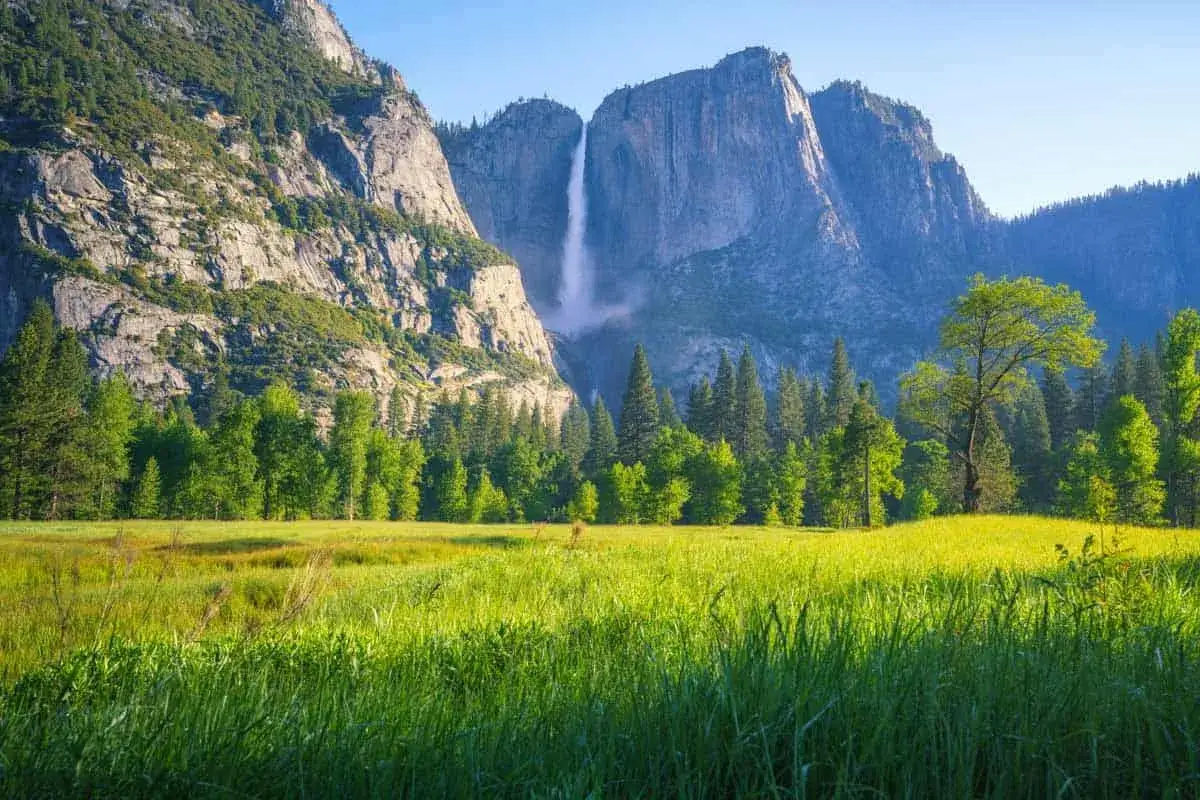 Wodospad Yosemite w Kalifornii, najpiękniejszy stan USA, otoczony zieloną łąką i majestatycznymi g&oacute;rami.
