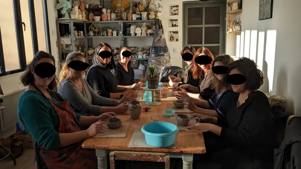 Des femmes participent à un atelier EVJF de poterie, créant des objets en argile dans une ambiance conviviale.