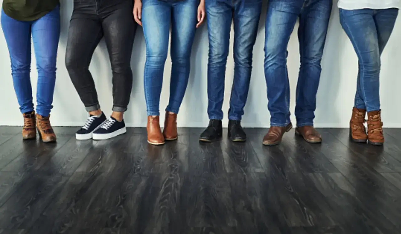 Un gruppo di persone indossa jeans slim fit, mostrando diverse tonalit&agrave; e calzature, dal casual all'elegante.