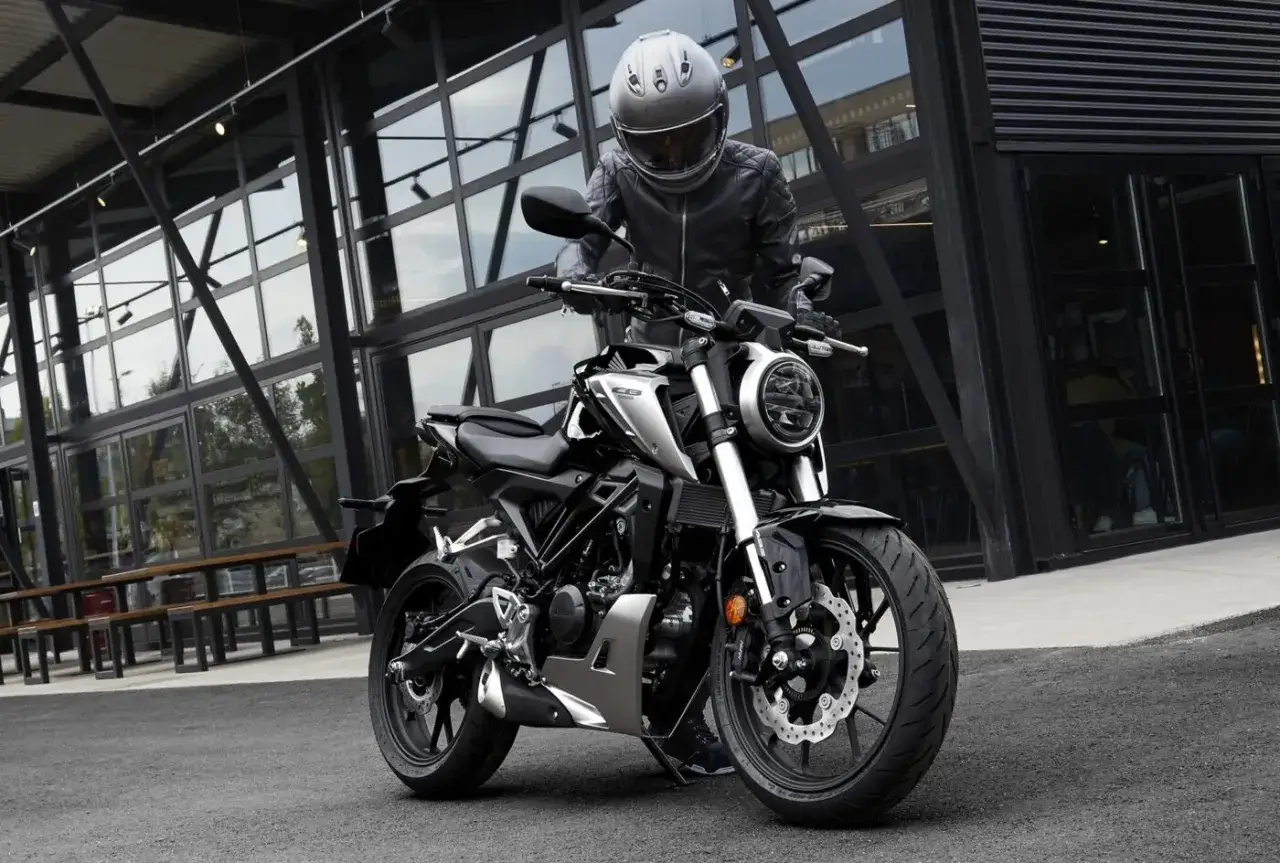 Mężczyzna w kasku i sk&oacute;rzanej kurtce przy czarnym motocyklu. To najmocniejszy motocykl na kat B, idealny na miejskie wyprawy.