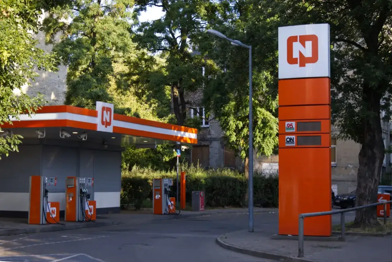 Stacja paliw z dystrybutorami i totemem informującym o cenach paliw w Warszawie.