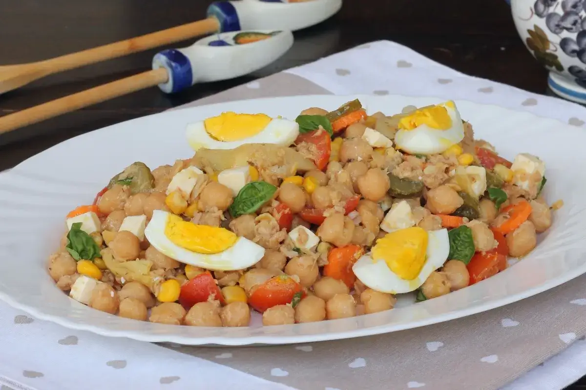 Insalata di ceci e tonno, ricca di uova sode, pomodorini, mais e cubetti di formaggio. Un piatto fresco e gustoso.