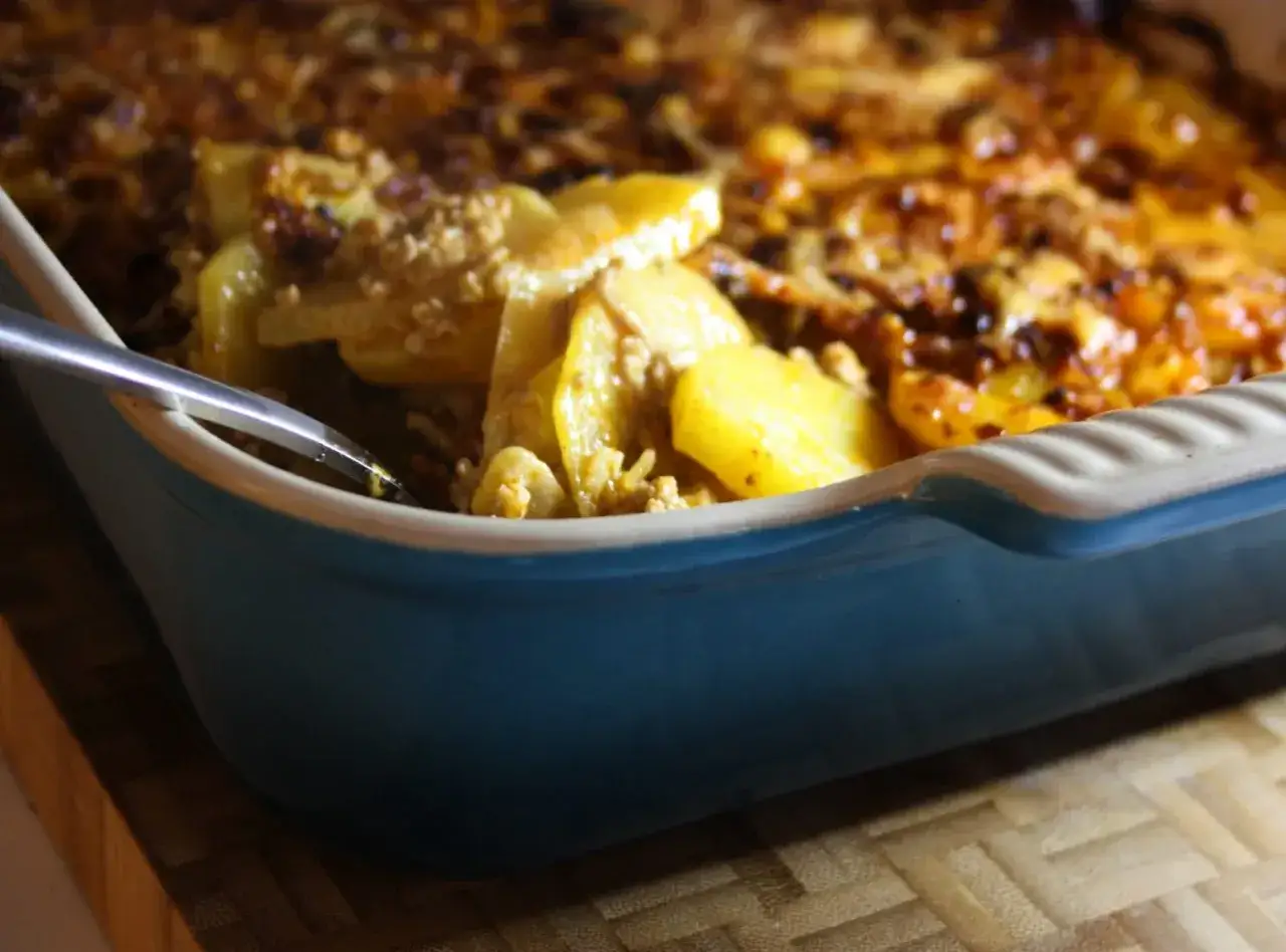 En bl&aring; ugnsform med gyllene potatis och k&ouml;ttf&auml;rs, redo att serveras. En h&auml;rlig mat i ugn som doftar ljuvligt.