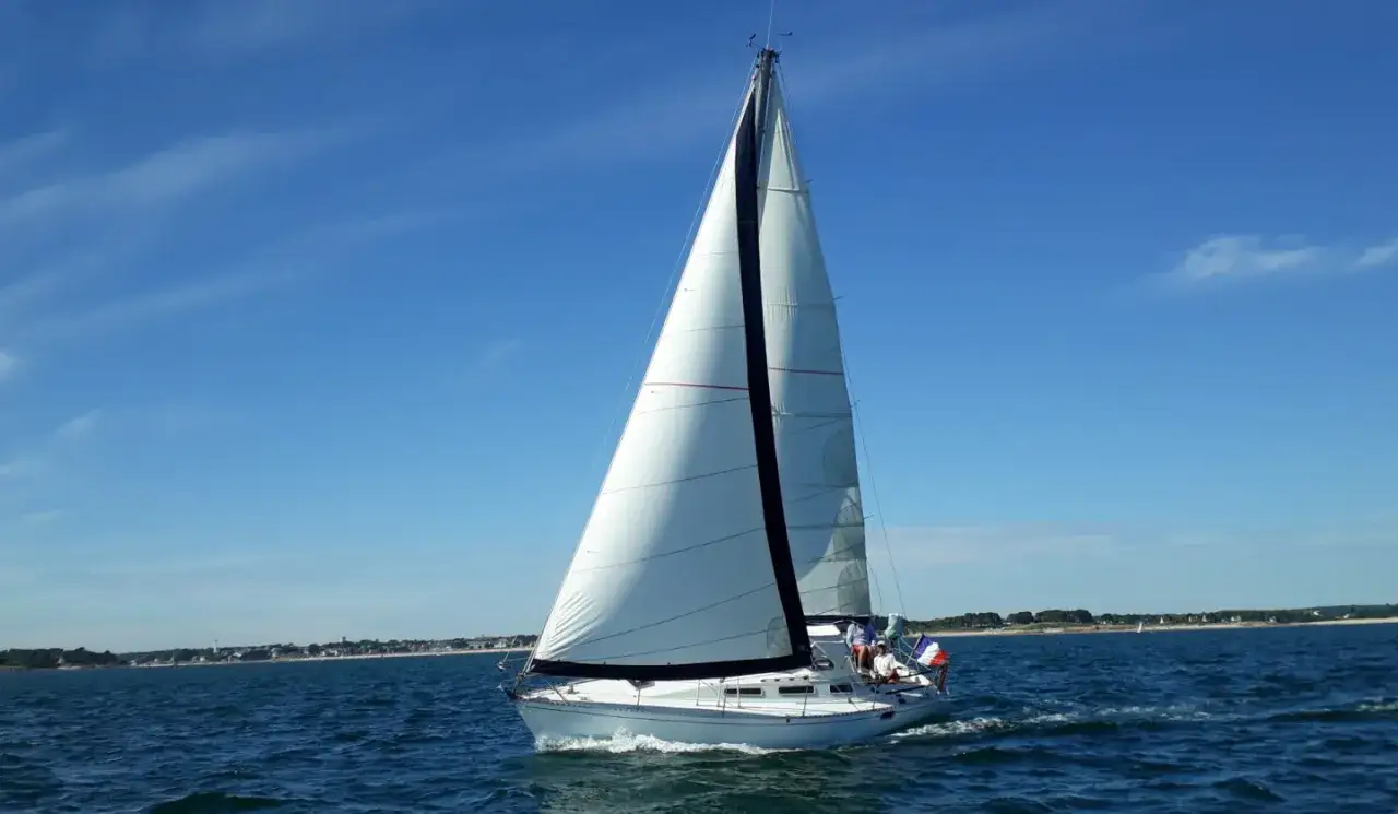 Voilier blanc naviguant sur une mer bleue sous un ciel clair. L'équipage semble profiter de la belle journée, un sentiment de 920 avis de bonheur.