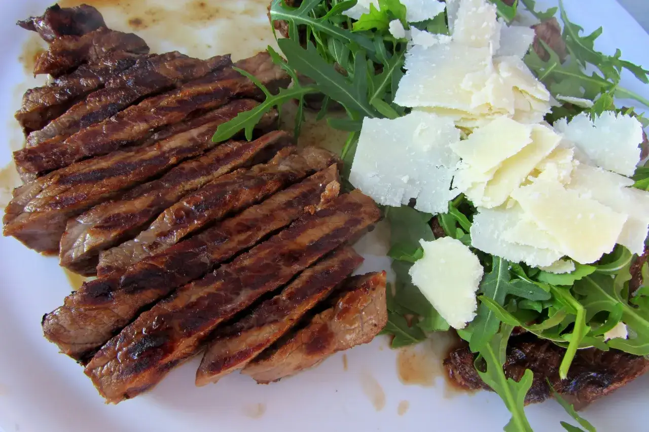 Pokrojona w plastry soczysta tagliata z rukolą i płatkami parmezanu.