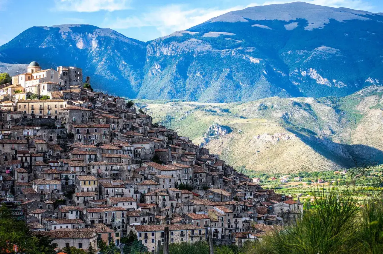 A picturesque village clinging to a hillside, with mountains in the background. A perfect example of where to visit in Calabria for stunning views.