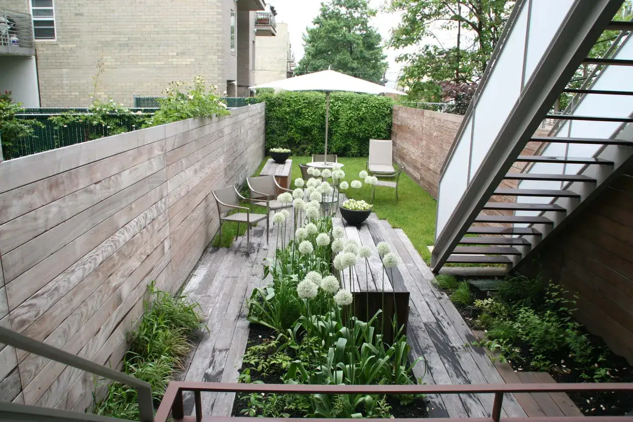 Moderner kleiner Garten mit Holzdeck und wei&szlig;en Zierlauchkugeln, perfekt f&uuml;r ein Reihenhaus.