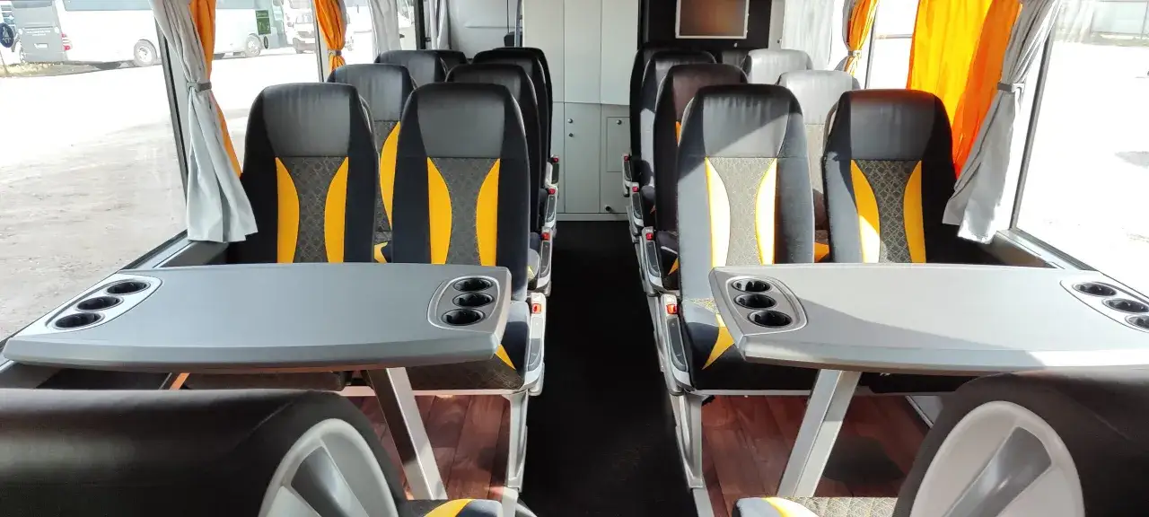 Wnętrze autokaru z wygodnymi siedzeniami i stolikami. Zastanawiasz się, ile kosztuje wynajem autokaru na wycieczkę?