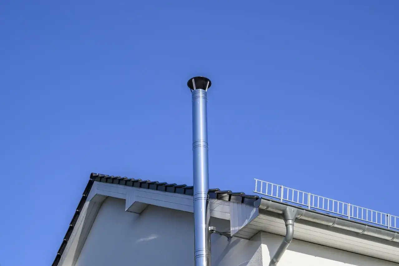 Edelstahlkamin ragt in blauen Himmel. Moderne Heiztechnik erm&ouml;glicht pelletofen ohne schornstein betreiben.