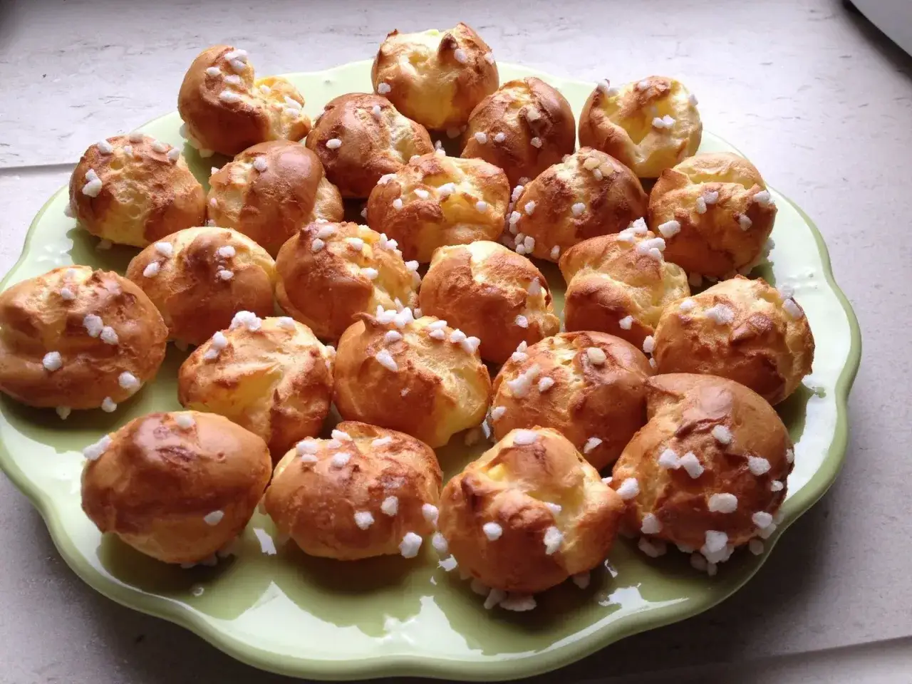 Une assiette de chouquettes traditionnelles dor&eacute;es et saupoudr&eacute;es de sucre perl&eacute;, pr&ecirc;tes &agrave; &ecirc;tre d&eacute;gust&eacute;es.