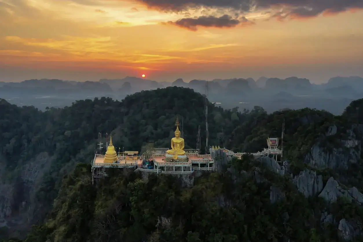 Goldener Buddha auf einem Bergplateau, Teil des Tiger Cave Temple, bei Sonnenuntergang.