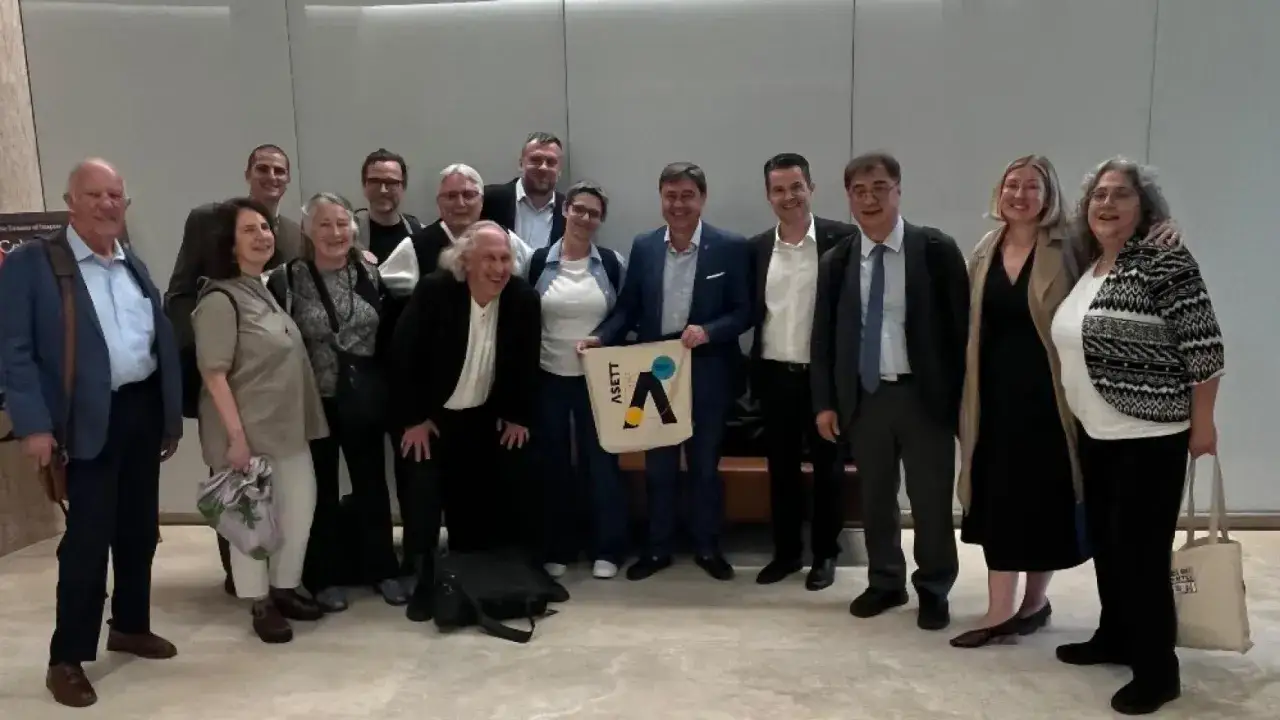 Grupo diverso posa para foto, algunos con bolsa de ASETT, representando una **empresa social** comprometida.