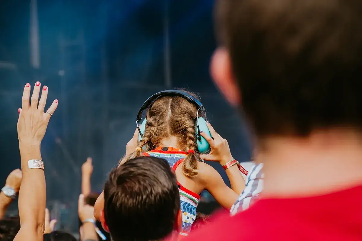 Une jeune fille aux tresses porte un casque anti-bruit, profitant de la musique. La sensation du bouchon oreille est là, protégeant ses tympans lors d'un concert.