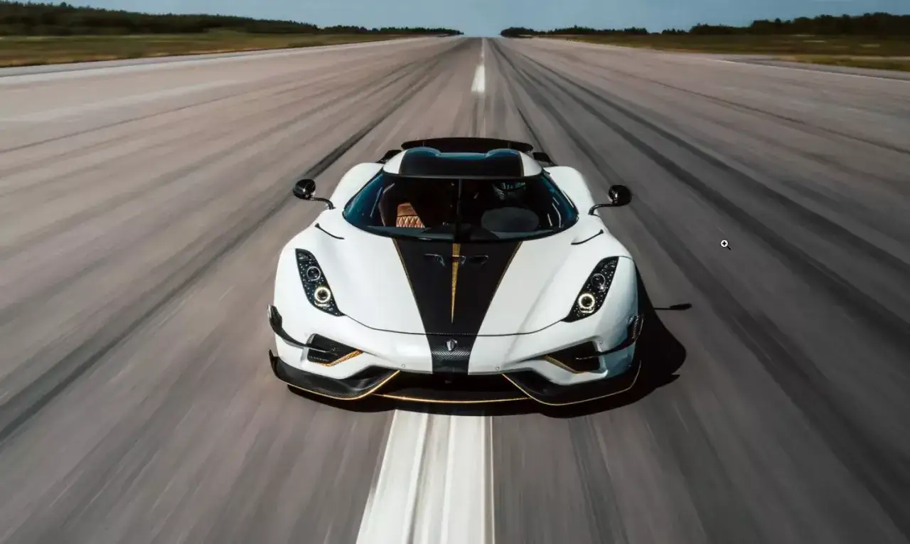 Biały Koenigsegg z czarnym pasem i złotymi akcentami pędzi po pasie startowym. Ta marka na k. jest niesamowita!