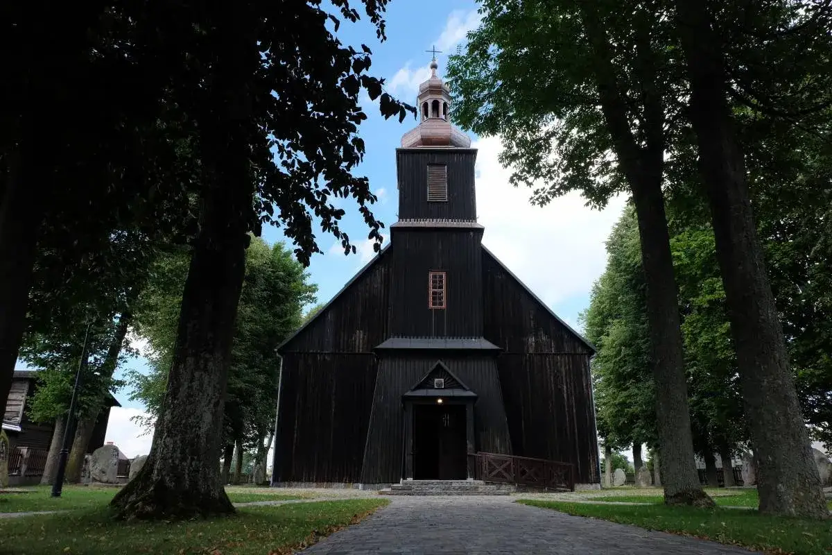 Drewniany kościół otoczony drzewami. Wygoda łączyńska, spokój i historia w jednym miejscu.