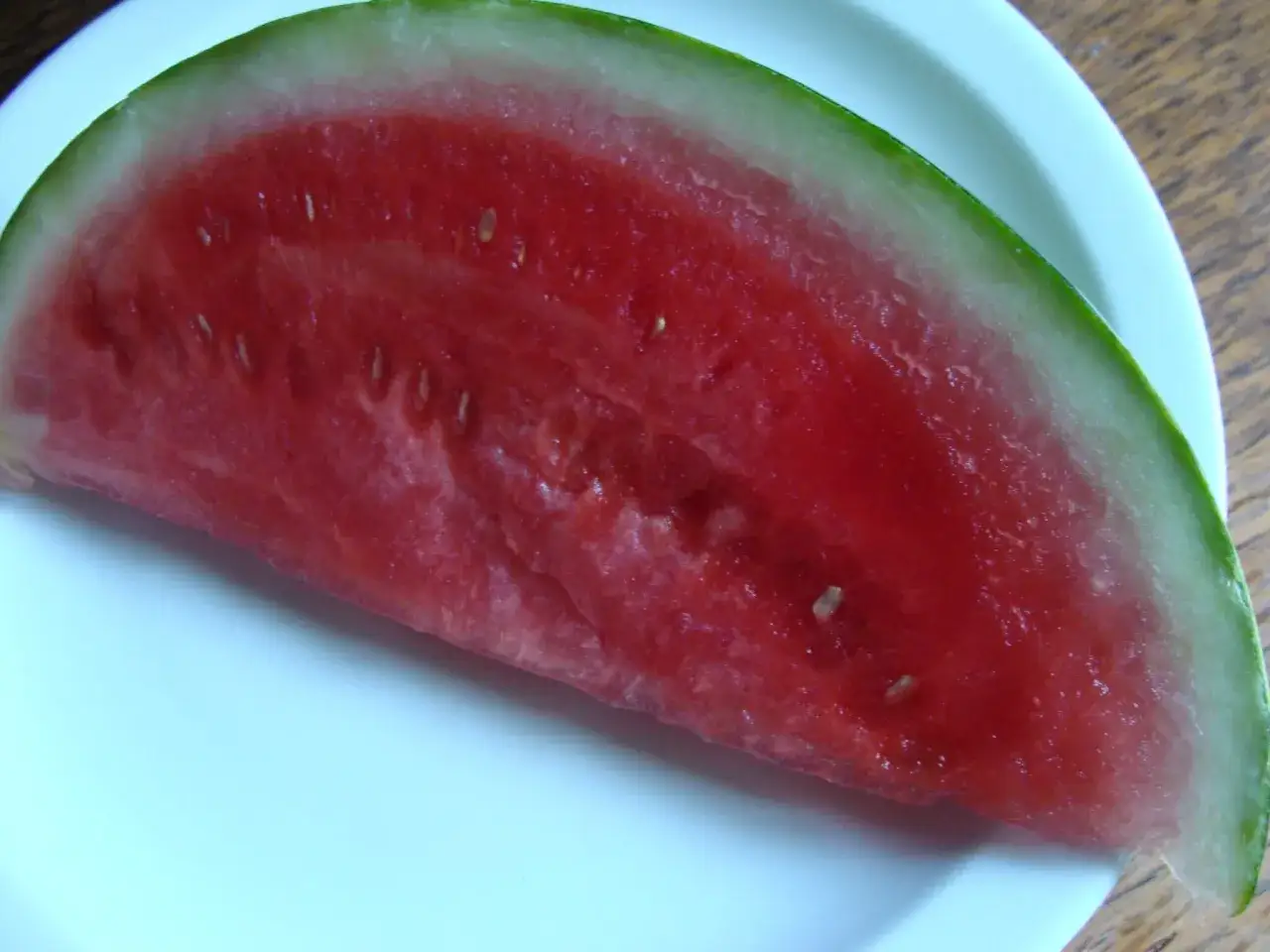 Tranche de pasteque bienfait sur une assiette blanche. Un d&eacute;lice rafra&icirc;chissant et plein de vitamines.