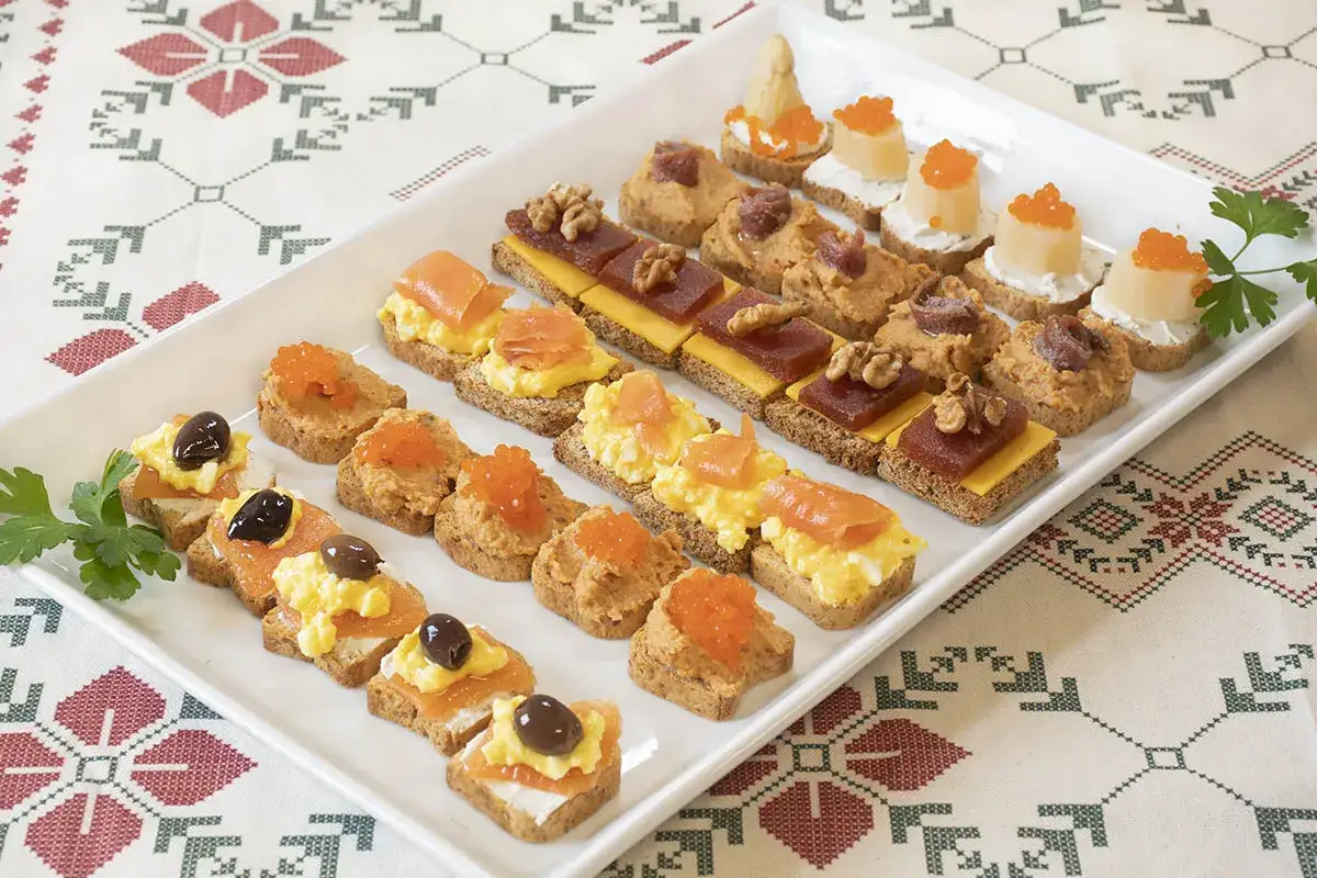 Bandeja con variedad de canapés: salmón, huevo, paté, caviar, queso y membrillo. Un picoteo fácil y rápido para cualquier ocasión.
