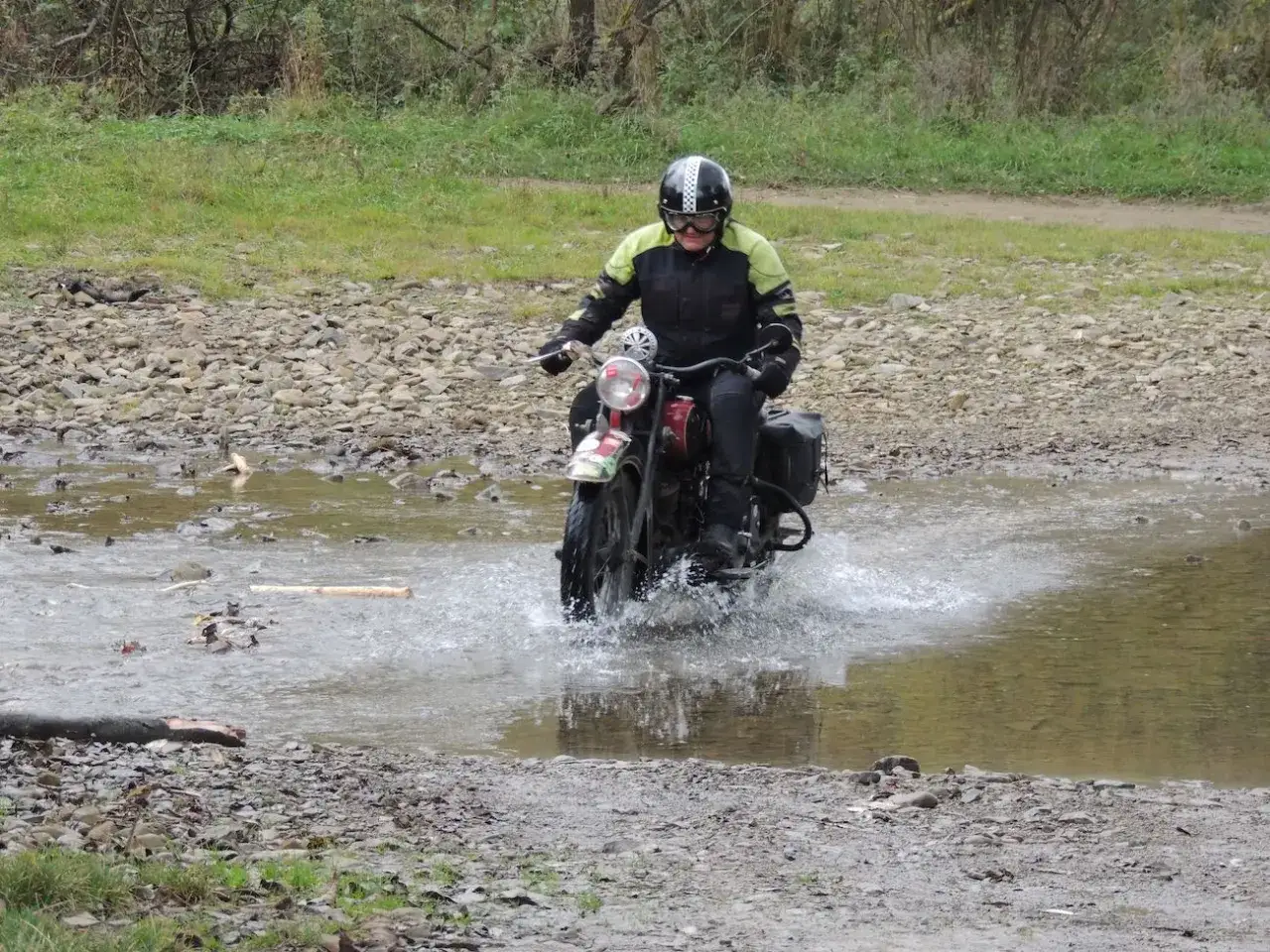 Motocyklista w kasku pokonuje wodną przeszkodę na trasie w okolicach Jasła.